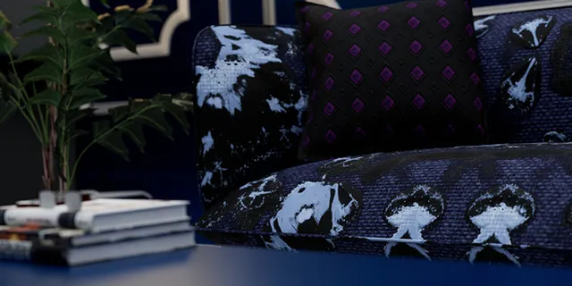 A dark blue couch dressed in patterned fabrics beside a plant and stacked books.